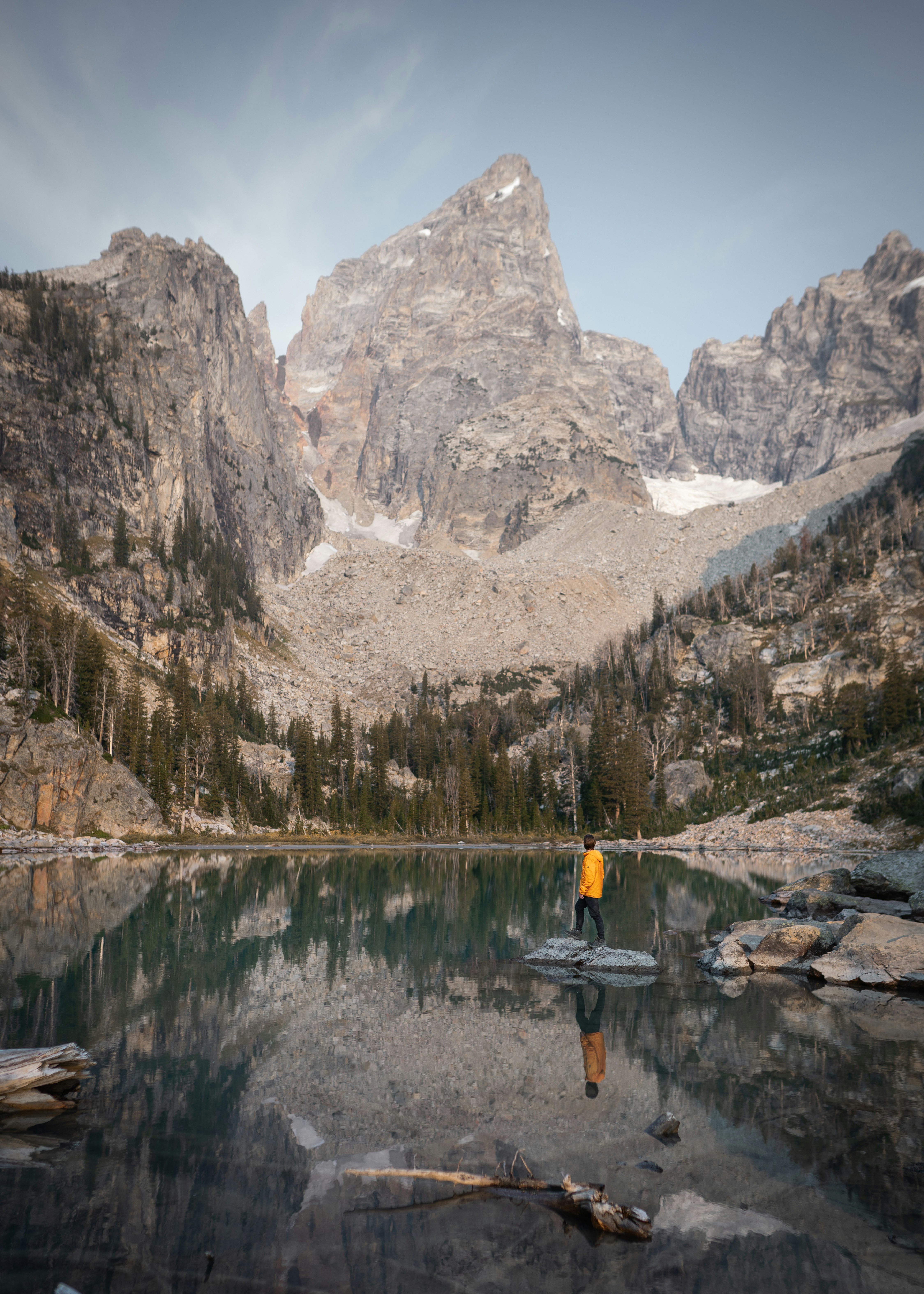 person in yellow jacket and black pants standing on boat on lake during daytime